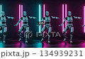 Robots performing synchronized dance moves in neon lit room with futuristic ambiance 134939231