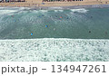 Aerial top-down drone view of surf lessons with beginner surfers waiting, paddling, and riding small waves near the shore in Bali, Indonesia. Popular beach activity and tropical surf lifestyle. 134947261