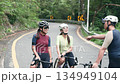 happy young asian cyclists chatting on roadside while training outdoors 134949104