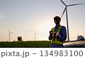 Engineer type the mobile and looking around the wind turbine site 134983100