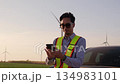 Engineer type the mobile and looking around the wind turbine site 134983101