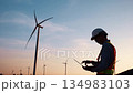 Engineer working with notebook inspector and checking in wind turbine field for power generation 134983103