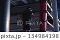 Close up of a male boxer during jump rope session. Against soft gym light, the boxer's silhouette flows effortlessly, combining strength and determination in a rhythmic jump rope session. 134984198