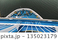 View from above of a ferry bow with blue deck and mooring equipment cutting through calm water 135023179