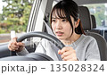 A young woman who is a paper driver and drives a car timidly 135028324