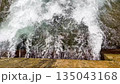 Top view of water flowing over a concrete dam structure, creating foam and turbulence, commonly found in hydropower plants and reservoirs 135043168