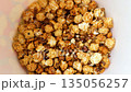 Eating popcorn from bottom of bucket. Remaining popcorn with unpopped kernels is eaten. Hand grabs the last of sweet caramel popcorn. The bucket is empty of caramel popcorn 135056257