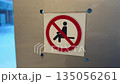 Sign on wall prohibiting sitting on windowsill. Don't sit here. Place where sitting is prohibited. Sign in red circle with rules prohibiting sitting in this area 135056261
