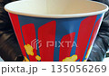 Cardboard bucket with caramel popcorn inside. Half empty bag of popcorn. Some of it was eaten after the movie. The concept of going to the cinema with sweet popcorn 135056269
