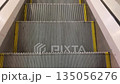 During descent, escalator steps align and retract under exit panel. Steel steps of modern escalator in motion. Concept of descent and completed journey. Descending from escalator 135056276