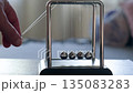 Hand Running Newton's Pendulum Close-Up	 135083283