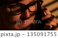Person Talking on Phone in Warm Lighting with Glasses 135091755