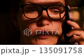 Woman with Glasses Talking on Phone in Warm Lighting 135091758