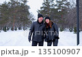 Romantic couple walking together in a snowy winter park 135100907