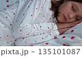 A 10-year-old girl sleeps sweetly in heart-shaped pajamas. High quality 4k footage 135101087