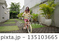 Mother teaching daughter to ride bicycle outdoors 135103665