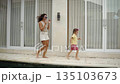 Mother and daughter running by the pool at their villa together at vacation 135103673
