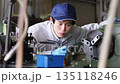 Male worker operating a machine in a factory 135118246