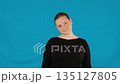 Lady stands with soft and amiable expression on blue background 135127805