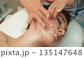 Spa, wellness, head massage, facial and skincare treatment. Anti-aging face massage, Masseuse hands during therapy. Woman receiving relaxing face massage at spa 135147648