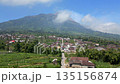 Aerial view of rural village with traditional houses and road leading toward Mount Merapi volcano in Central Java, Indonesia. Scenic landscape showing everyday life near an active volcano. 135156874