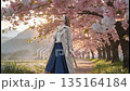 A woman walking along a row of cherry blossom trees, petals flying everywhere 135164184