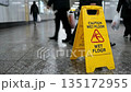 Yellow Caution Wet Floor sign standing on tiled floor in busy hallway. 135172955