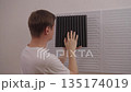 Back view of young adult man comparing different soundproofing acoustic panels and placing them on wall for noise reduction, improving room acoustics for sound recording or home studio, slow motion. 135174019