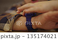 Close-up of young boy wearing blue smartwatch on wrist, finger interacting with device screen, symbolizing childhood engagement with wearable technology and connectivity. Shooting in slow motion. 135174021