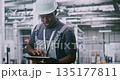Professional Factory Employee Supervises Robotic Machinery Using Mobile Control Device 135177811