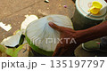 Close up shot hand removes green husk from young coconut preparing drink for customer 135197797