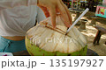 Woman drinking fresh young coconut water with straw at roadside local cafe in Nusa Penida Bali 135197927