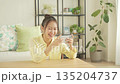 A smiling Japanese woman watching a video on her smartphone in the living room 135204737