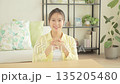 Smiling young Japanese woman having a conversation while looking at the camera in the living room 135205480