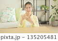 Smiling young Japanese woman having a conversation while looking at the camera in the living room 135205481
