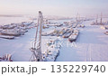 Snowcovered boats in harbor viewed from above, against urban skyline 135229740