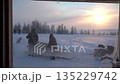 Two people standing by a snowmobile in a snowy natural landscape 135229742