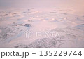 Aerial view of snowy landscape under pink sky with clouds 135229744