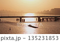 Aerial view of barge travels on Qiantang River under bridges in Hangzhou during golden hour sunset illuminating the water 135231853