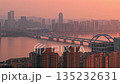 A view of Hangzhou shows an urban area with tall buildings, a large bridge spanning the river at sunset. 135232631