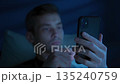 Man a dark bedroom, holding mobile phone and browsing social media at night 135240759