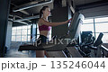 A young beautiful woman in sportswear is training and exercising on a treadmill in a gym 135246044