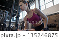Young beautiful woman in sportswear training and doing exercises for arms and biceps with dumbbells in the gym 135246875