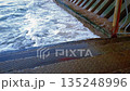 Close-up of clear turquoise coastal surf waves breaking on damaged concrete steps of old stone staircase on seafront embankment on Baltic Sea coast. Water force natural background, high angle shot. 135248996