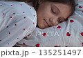 A 10-year-old girl sleeps sweetly in heart-shaped pajamas. High quality 4k footage 135251497
