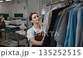 A woman worker hangs freshly washed clothes on a rack in a laundromat 135252515