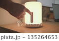 Close up of a male hand adjusting brightness level of a smart lamp. 135264653
