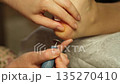 Expert hands provide a soothing pedicure, addressing foot care using specialized tools in a tranquil salon, ensuring a refreshing experience for clients. 135270410