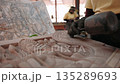 Close up of hands carve a traditional khmer apsara bas relief on stone in a workshop, using a chisel and mallet. Siem reap, Cambodia. 135289693