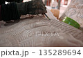 Close up of hands carve a traditional khmer apsara bas relief on stone in a workshop, using a chisel and mallet. Siem reap, Cambodia. 135289694